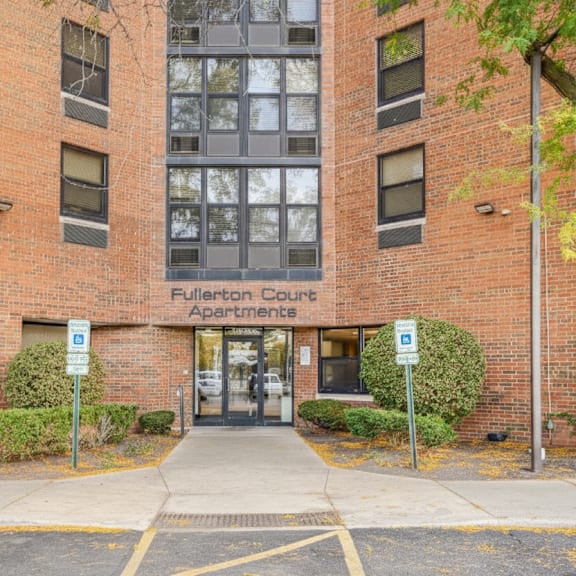the image shows the front of fullerton county apartments with a brick facade and a glass door entrance at fullerton court apartments, illinois 60614