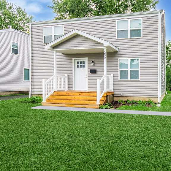 a house with a grey exterior and a white door is surrounded by a green lawn at poplar place apartments, springfield, il 62703