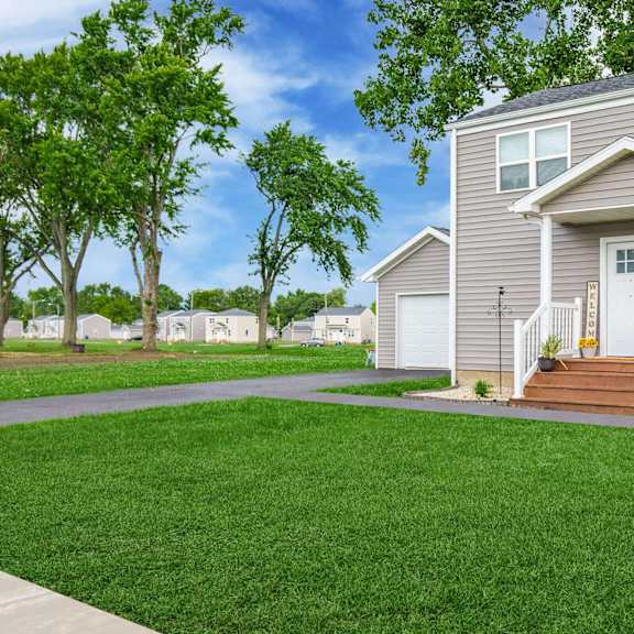 a house with a grey siding and a white door is surrounded by a green lawn at poplar place apartments, springfield, 62703