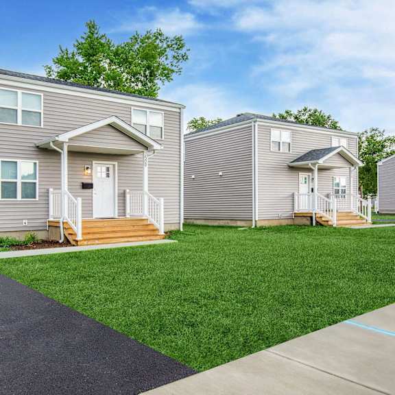 a grey house with a white door and windows is surrounded by a green lawn at poplar place apartments, springfield, illinois