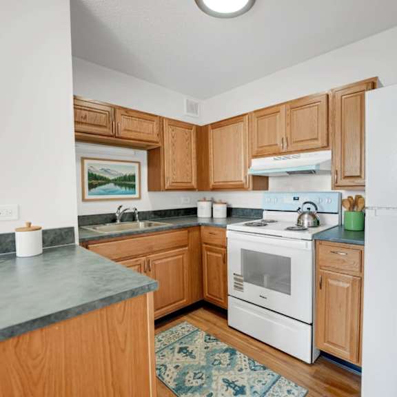 a kitchen with wooden cabinets and a white refrigerator at fullerton court apartments, chicago, il 60614