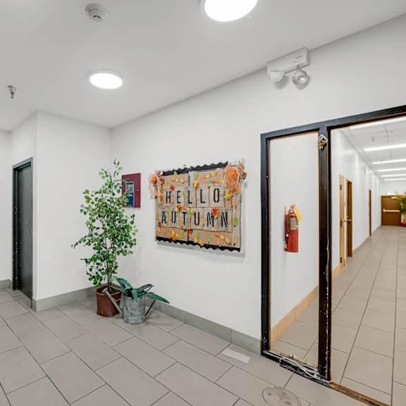 a hallway with a plant, a poster, and a fire extinguisher at fullerton court apartments, illinois