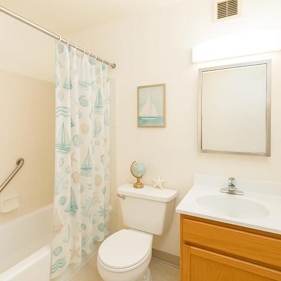 a bathroom with a toilet, sink, and shower curtain at mohican apartments, new london, ct, 06320