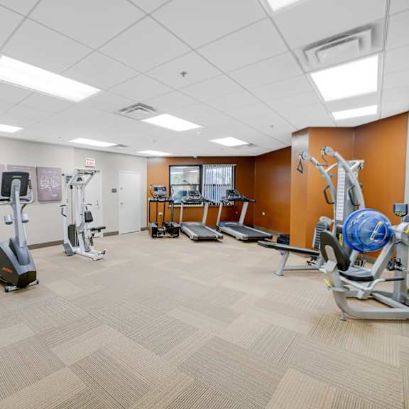 a gym with a variety of equipment including treadmills, stationary bikes, and weight machines at fullerton court apartments, chicago
