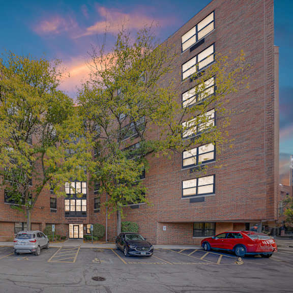 a parking lot in front of a brick building with cars parked at fullerton court apartments, chicago, illinois
