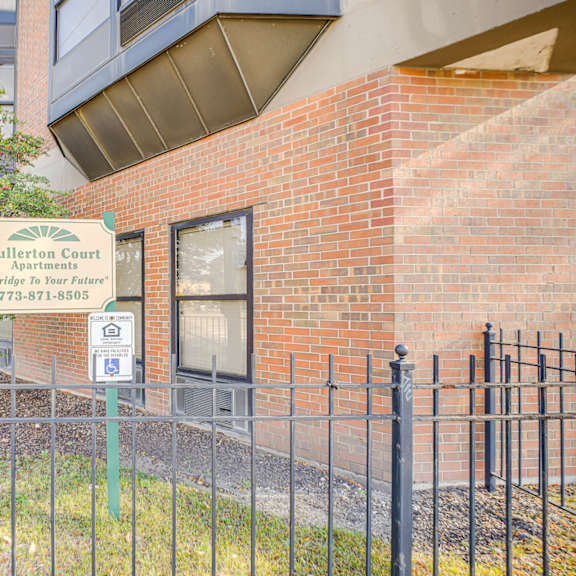 a sign for fullerton court apartments is displayed in front of a brick building at fullerton court apartments, chicago, il