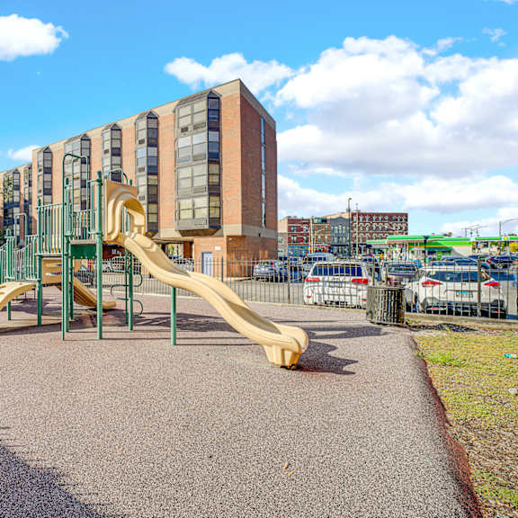 a playground with a yellow slide in front of a building at fullerton court apartments, chicago, il 60614