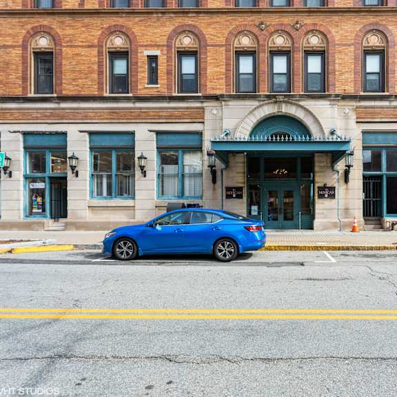 a blue car is parked in front of a building with a green awning at mohican apartments, new london, connecticut