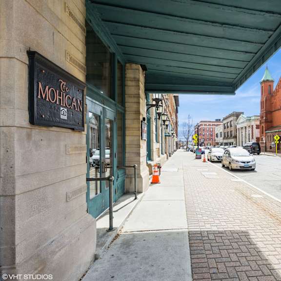 a street view with cars parked on the side and a building with a sign at mohican apartments, new london, ct