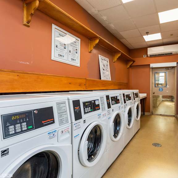 a row of washing machines in a public laundromat at mohican apartments, new london