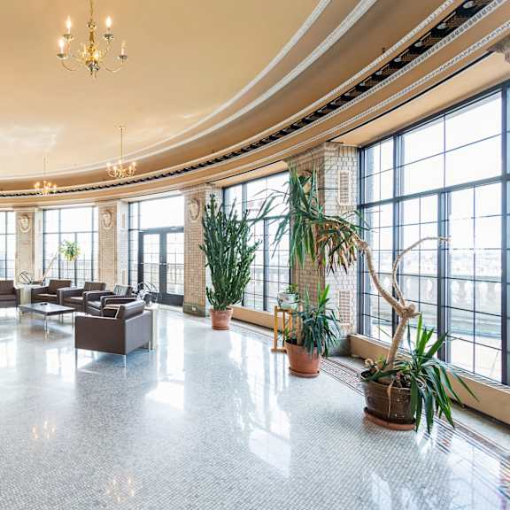 a spacious room with a high ceiling, large windows, and a variety of plants at mohican apartments, connecticut