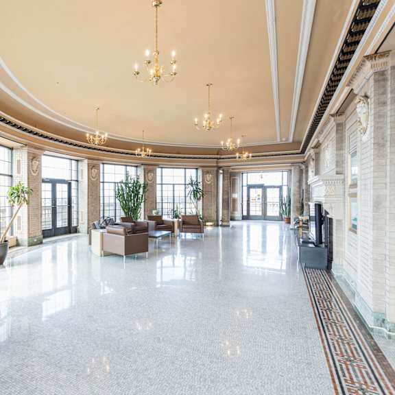 a large, well-lit atrium with a marble floor and a variety of plants at mohican apartments, new london, ct, 06320
