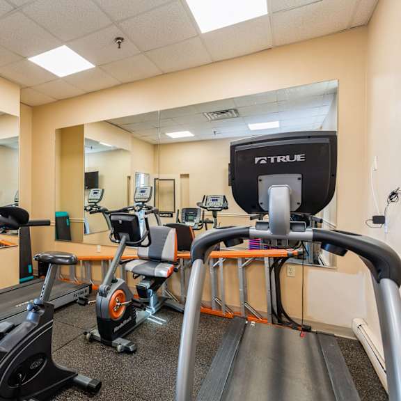a gym with treadmills, exercise bikes, and a television at mohican apartments, new london