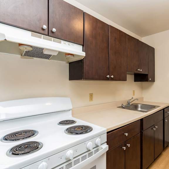 a white stove in a kitchen with brown cabinets at mohican apartments, new london, connecticut