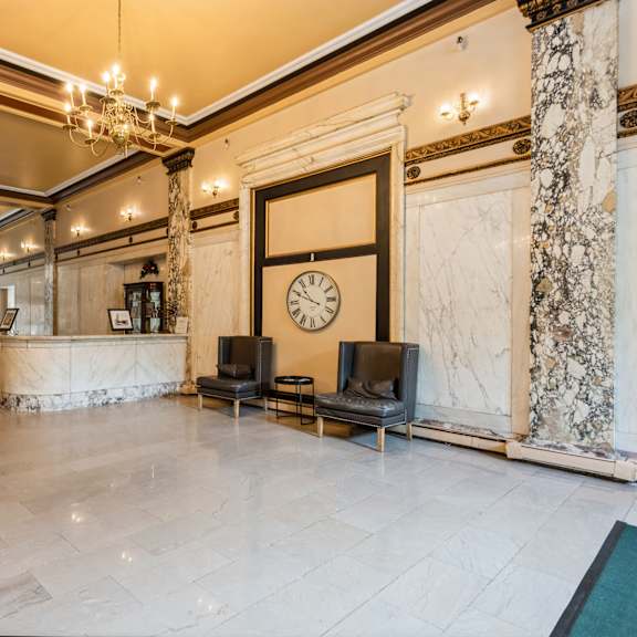 a large, elegant room with a marble floor and a clock on the wall at mohican apartments, new london, 06320