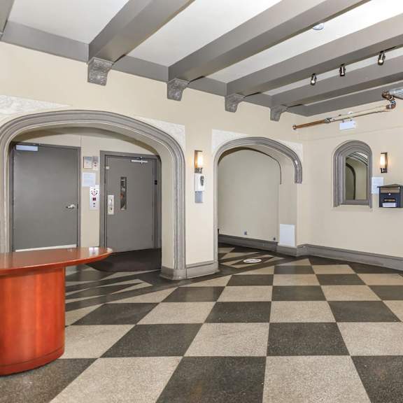 a hallway with a black and white checkered floor and a red reception desk at sheridan park, chicago, 60640