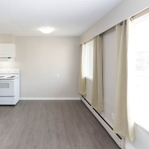a kitchen with white appliances and a window with curtains.