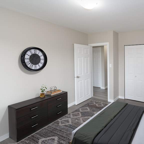 a bedroom with a bed, dresser, and a clock on the wall.