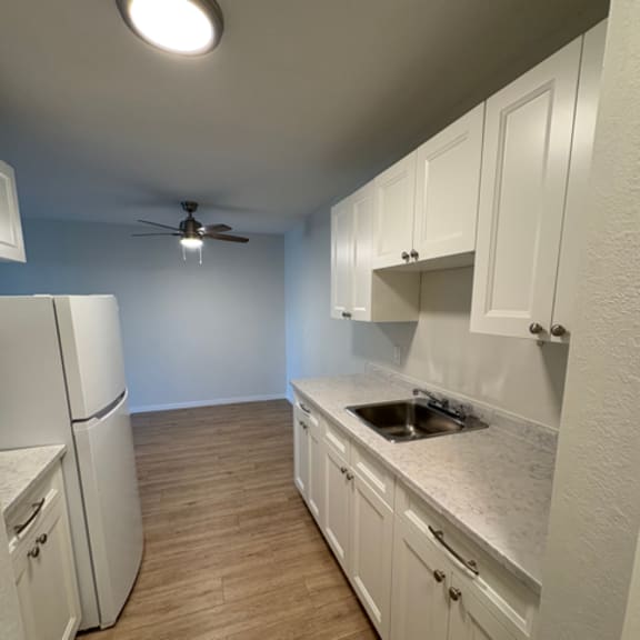 a kitchen with white cabinets and a ceiling fan.