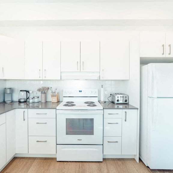 a white kitchen with a refrigerator on the right.