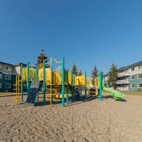 a playground with a yellow and green slide in the foreground.