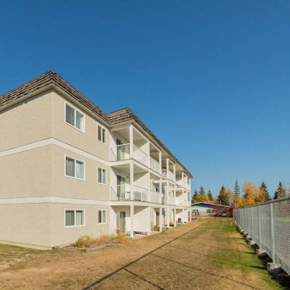 a large beige apartment building with multiple balconies and windows.