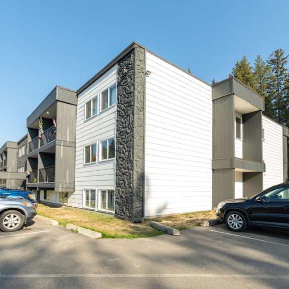 a modern two-story building with a parking lot in front.