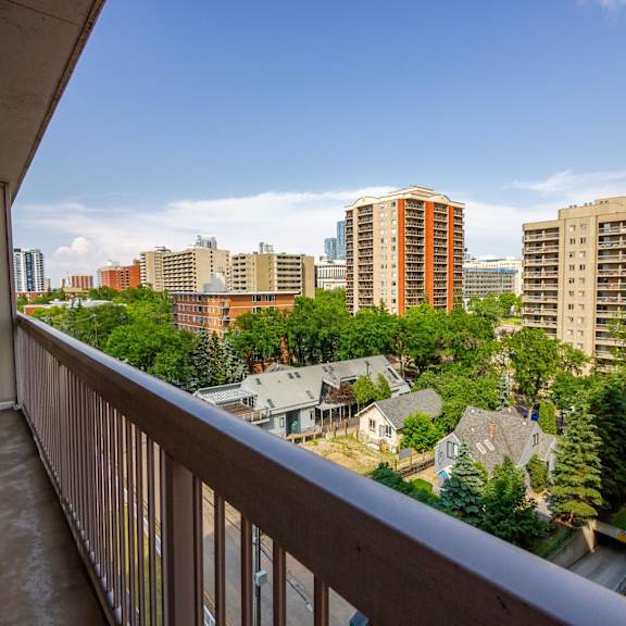 a balcony overlooks a residential area with houses and tall buildings.