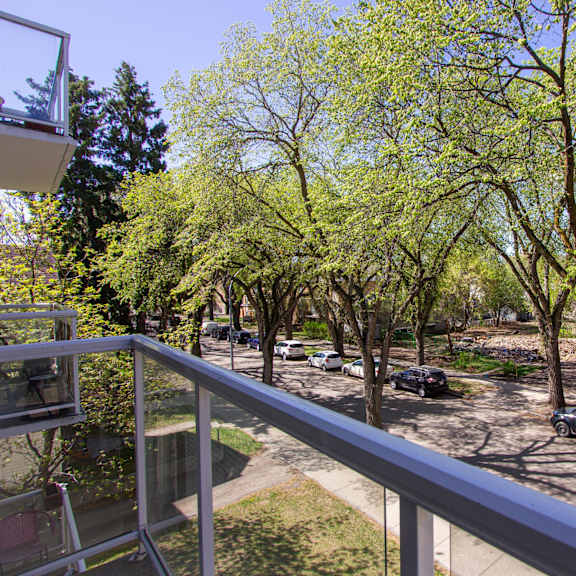 a balcony overlooks a parking lot with cars and trees.