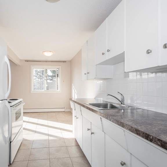 a kitchen with white cabinets and a white refrigerator.