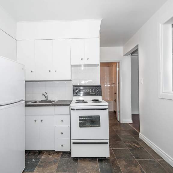 a white kitchen with a refrigerator, sink, and stove.