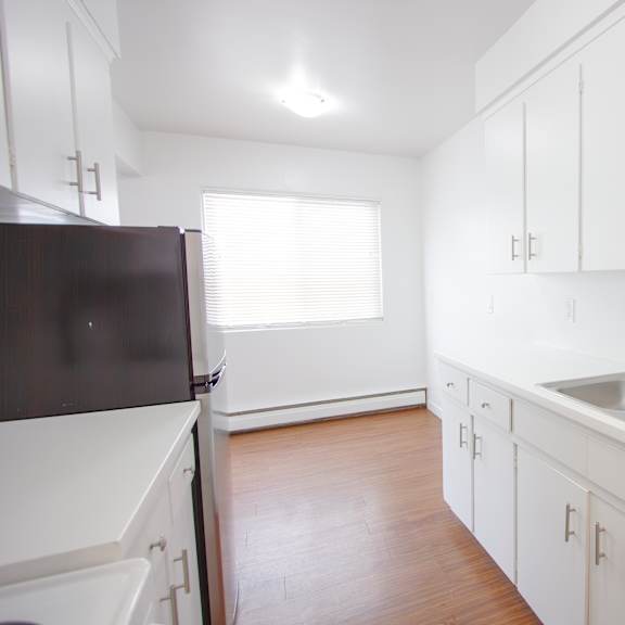 a kitchen with white cabinets and a black refrigerator.