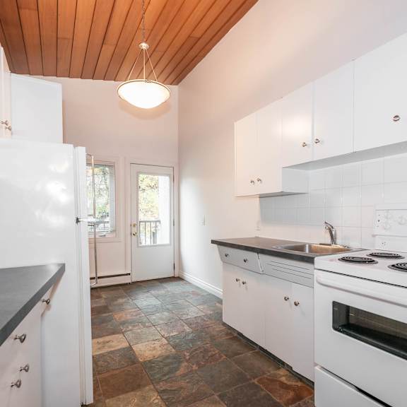 a modern kitchen with white cabinets and a wooden ceiling.