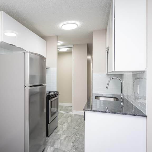 a kitchen with a refrigerator, oven, and sink.