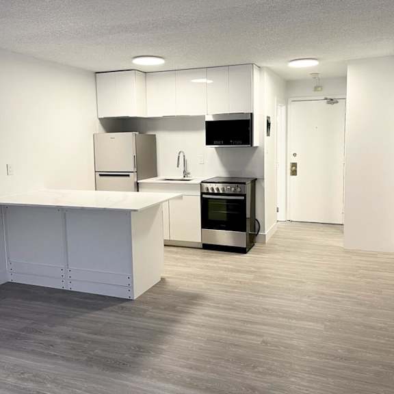 a modern kitchen with a white countertop and stainless steel appliances.