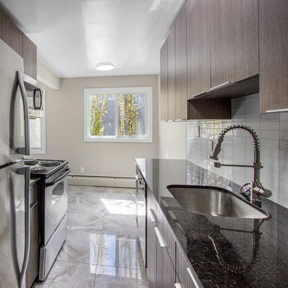 a modern kitchen with a stainless steel refrigerator and a black countertop.