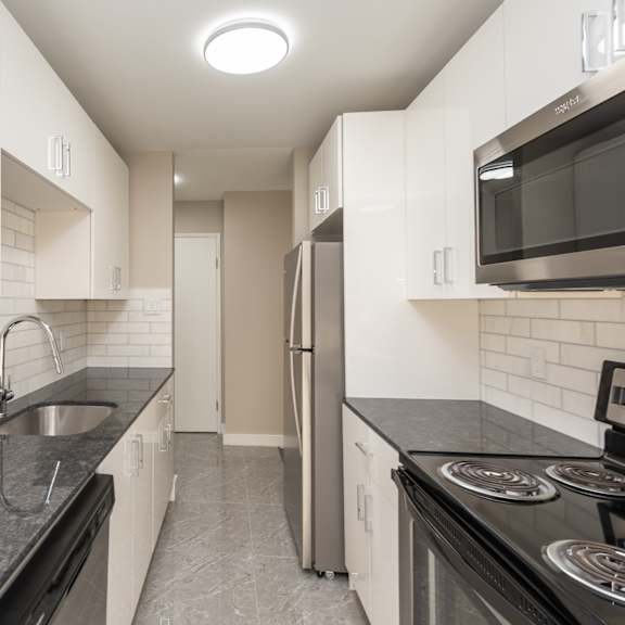 a kitchen with black countertops and white cabinets.