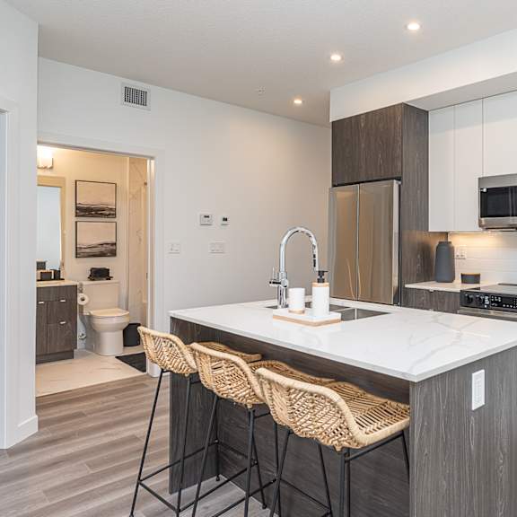 a modern kitchen with a white countertop and wooden cabinets.