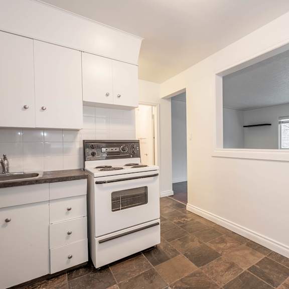 a kitchen with white cabinets and a tiled floor.