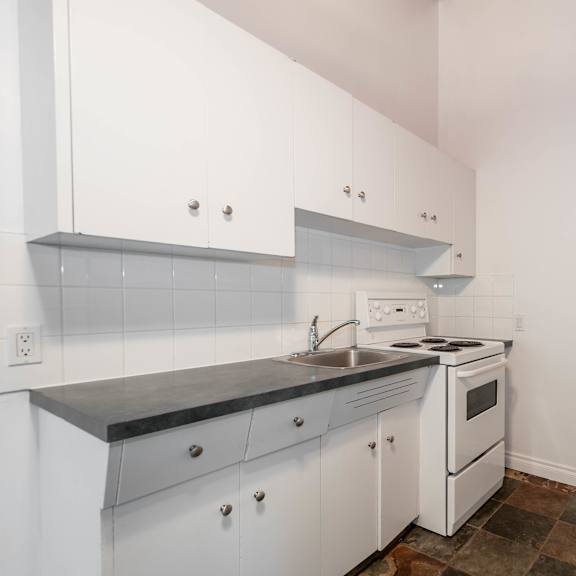 a kitchen with white cabinets and a black counter top.