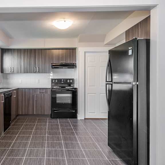 a kitchen with a black refrigerator and brown cabinets.