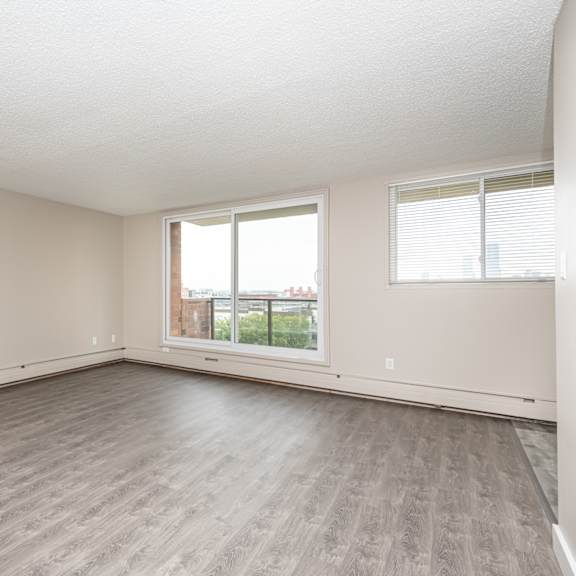 a spacious room with wooden flooring and a large window.
