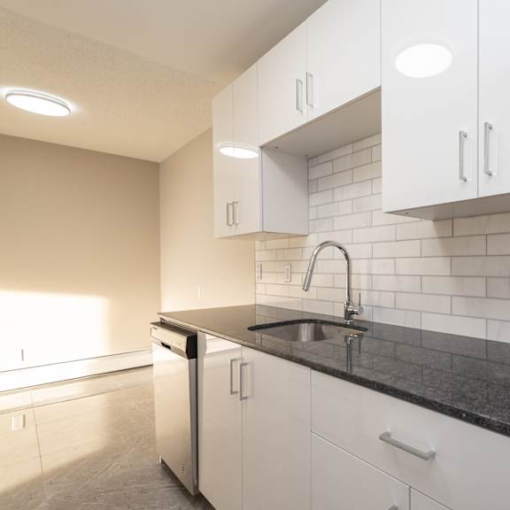 a kitchen with white cabinets and a black countertop.