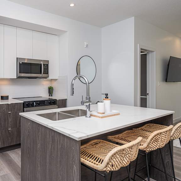a modern kitchen with a stainless steel refrigerator, a microwave, and a white countertop.