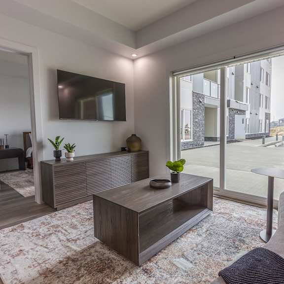 a modern living room with a large coffee table and a flat screen tv mounted on the wall.