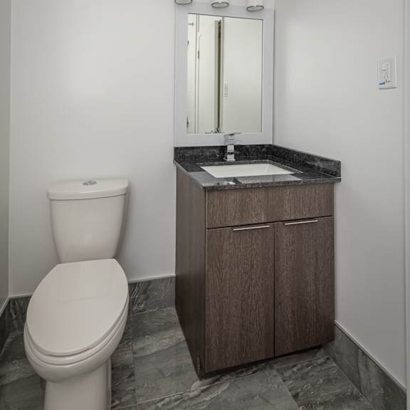 a bathroom with a toilet, sink, and mirror.