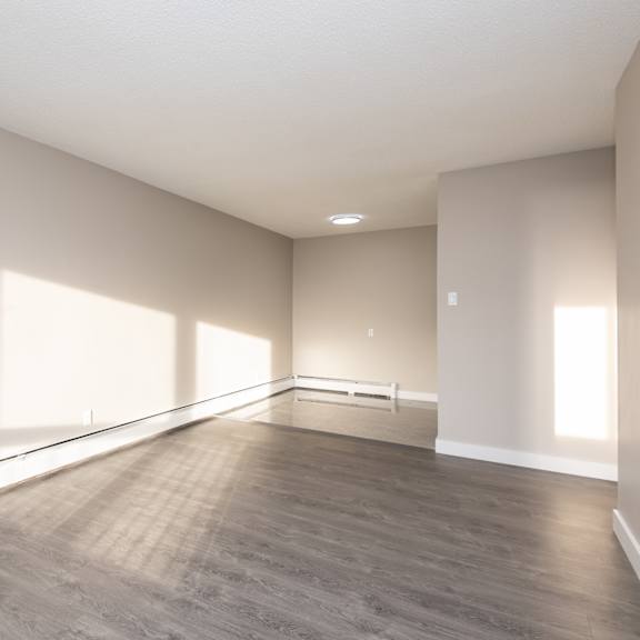 a large empty room with wooden flooring and white walls.