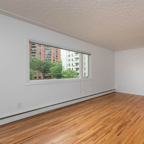 a room with wooden floors and a window showing a view of a building outside.