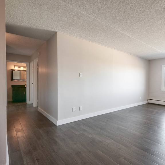 a spacious room with wooden flooring and a window.