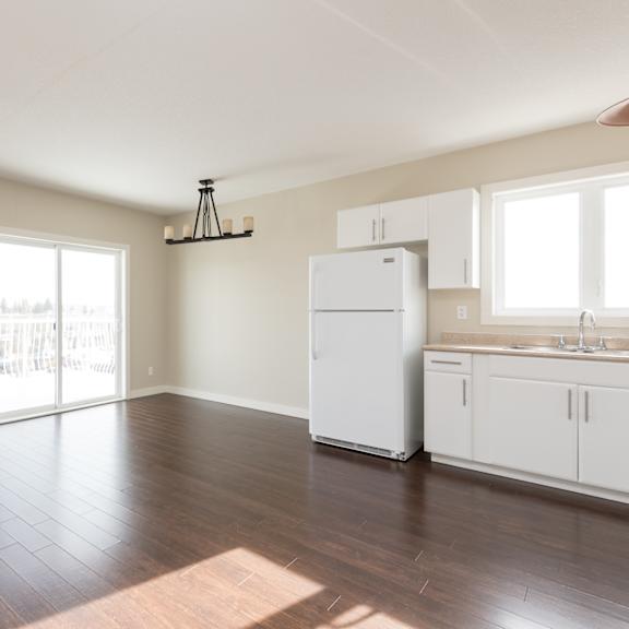 a kitchen with white appliances and wooden floors.